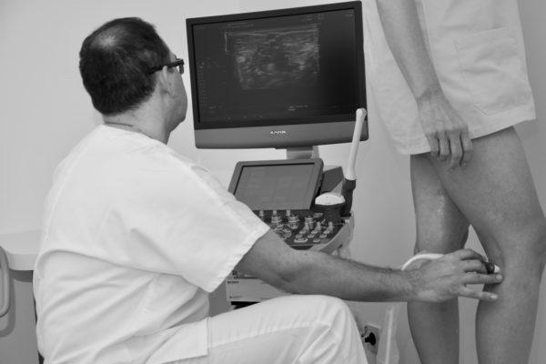 zdravnik z ultrazvokom pregleduje krčne žile, bolečine v nogah